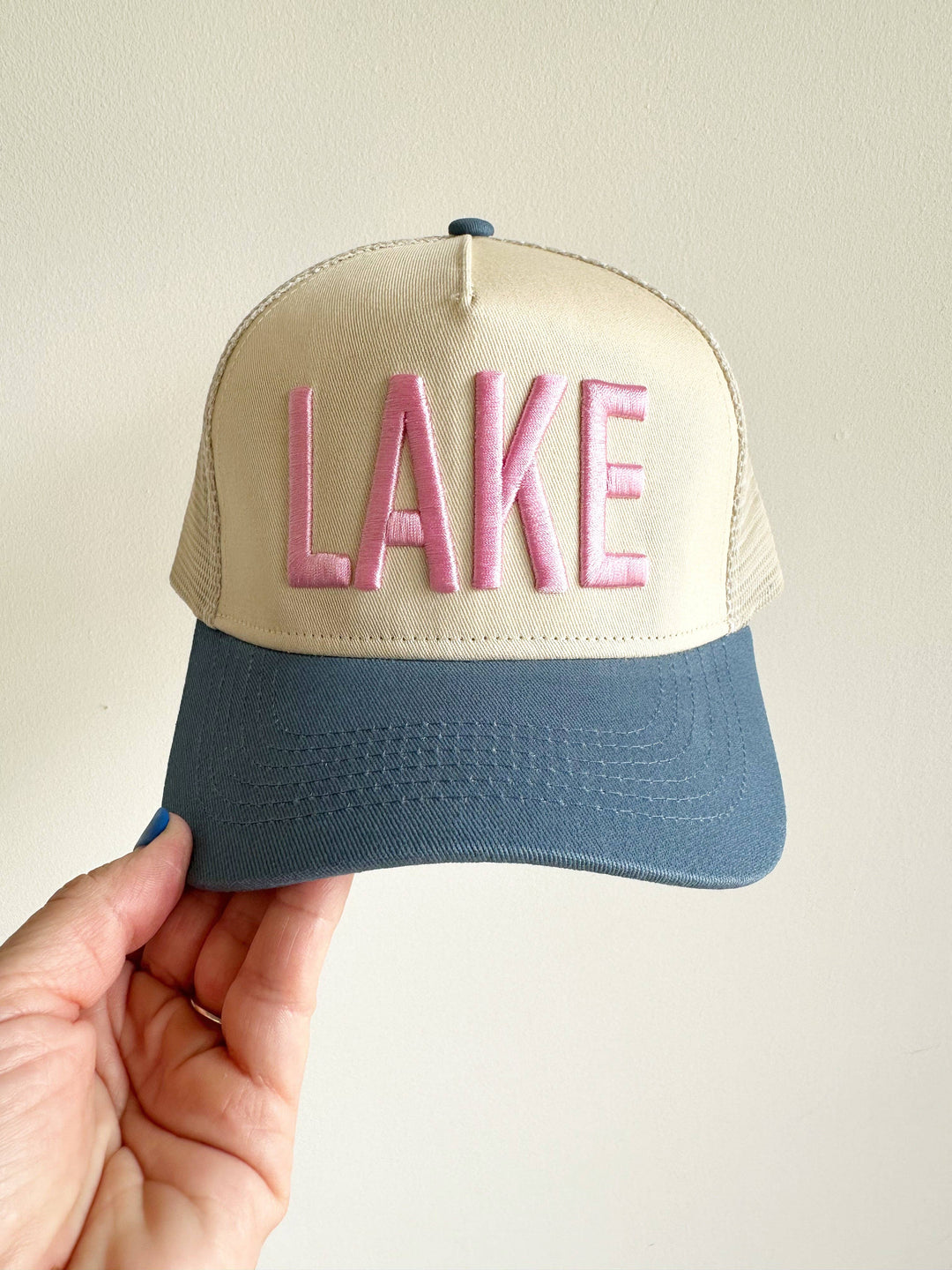 Beige and blue cap with 'LAKE' in pink on a beige background