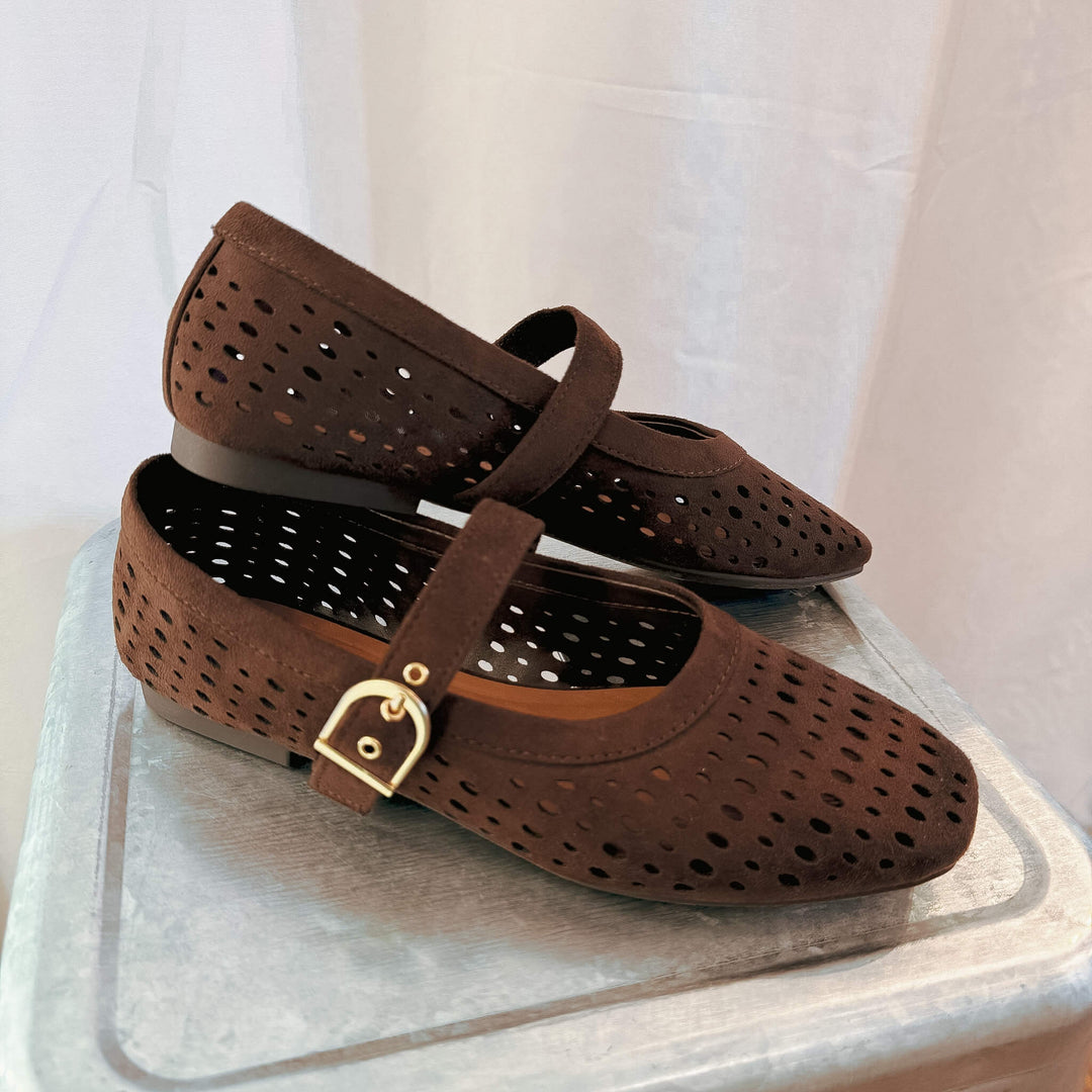 A pair of dark brown perforated Mary Jane flats with a gold-tone buckle